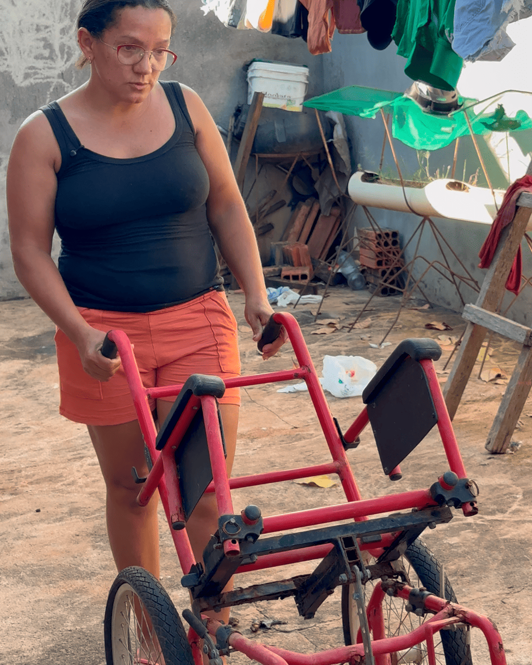 Maria Sônia segurando o equipamento de mobilidade de Ana Júlia